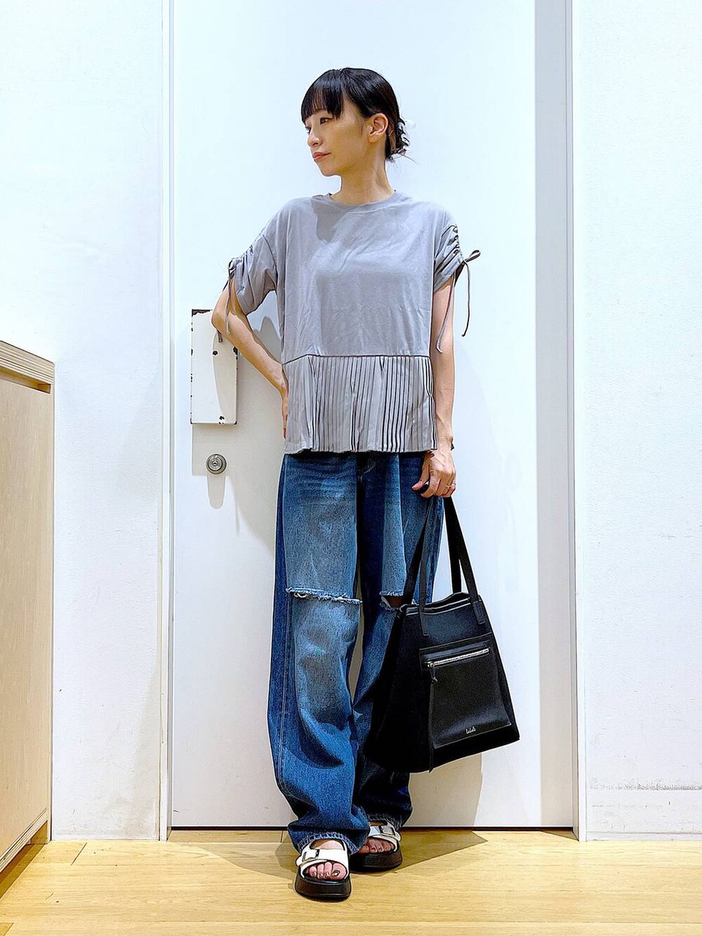ホワイト系のサンダル、ブラック系のトートバッグ、ブルー系のデニムパンツを着用したレディースの夏コーディネートの2枚目の写真