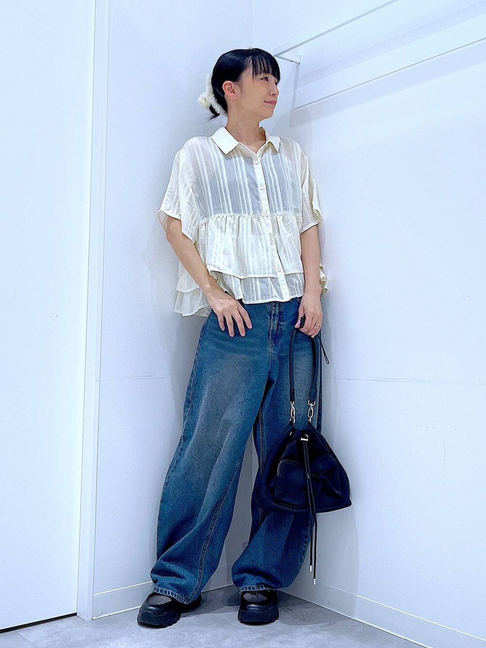 ブルー系のデニムパンツ、ブラック系のスニーカー、ブラック系のショルダーバッグを着用したレディースの春コーディネートの2枚目の写真