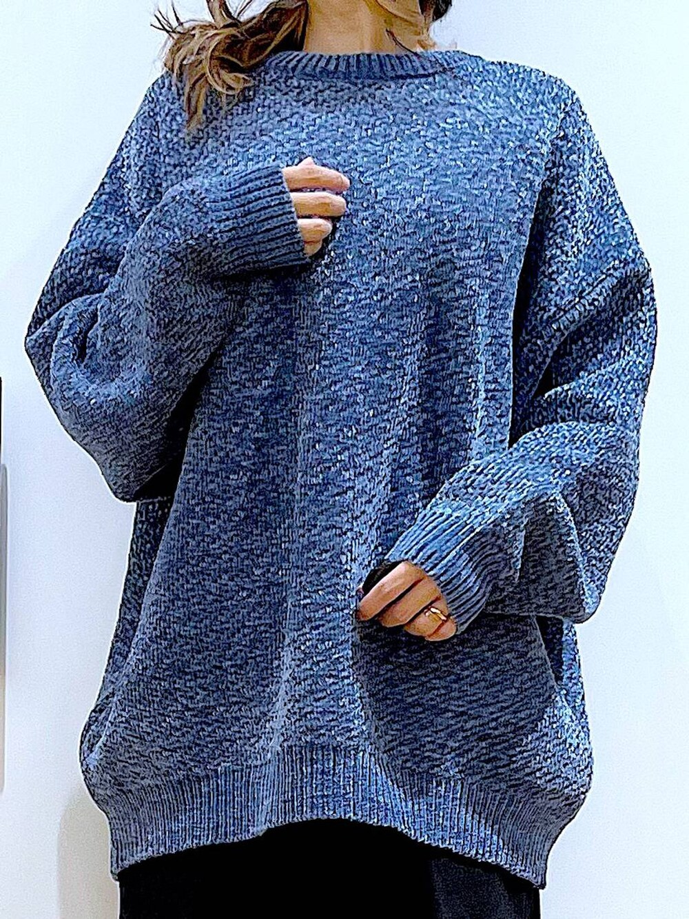 ブルー系のニット/セーター、ホワイト系のクラッチバッグ、ブラック系のブーツを着用したレディースの冬コーディネートの7枚目の写真