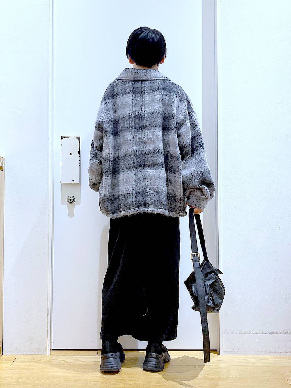 グレー系のジャンパースカート、ブラック系のブーツ、ブラック系のショルダーバッグを着用したレディースの冬コーディネートの5枚目の写真