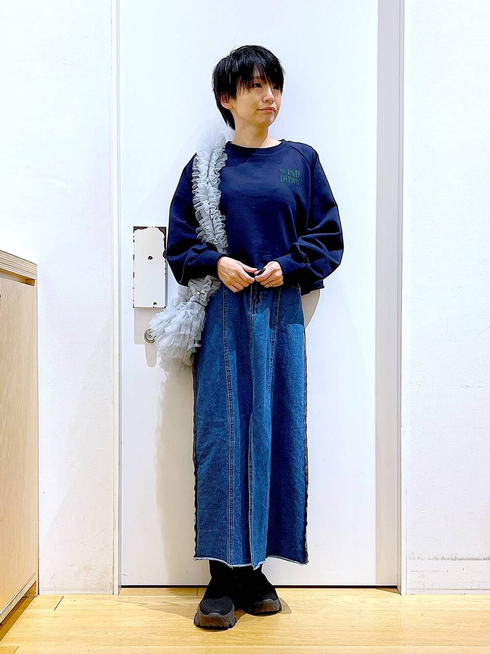 ブルー系のデニムスカート、ブラック系のブーツ、グレー系のショルダーバッグを着用したレディースの冬コーディネートの2枚目の写真