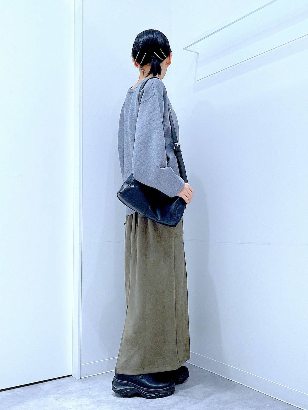 ブラック系のショルダーバッグ、ブラック系のブーツ、グリーン系のスカートを着用したレディースの冬コーディネートの4枚目の写真