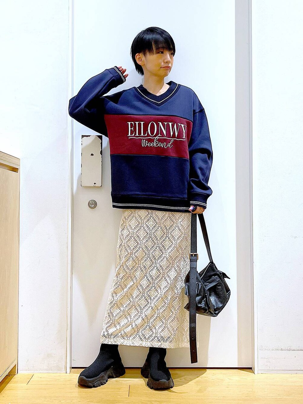 ブラック系のブーツ、ホワイト系のスカート、ブラック系のショルダーバッグを着用したレディースの冬コーディネートの2枚目の写真