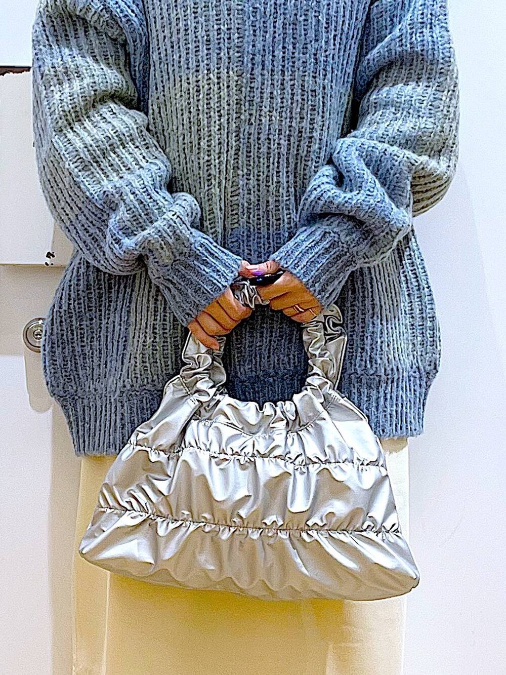 ブルー系のニット/セーター、ブラック系のブーツ、シルバー系のショルダーバッグを着用したレディースの冬コーディネートの9枚目の写真