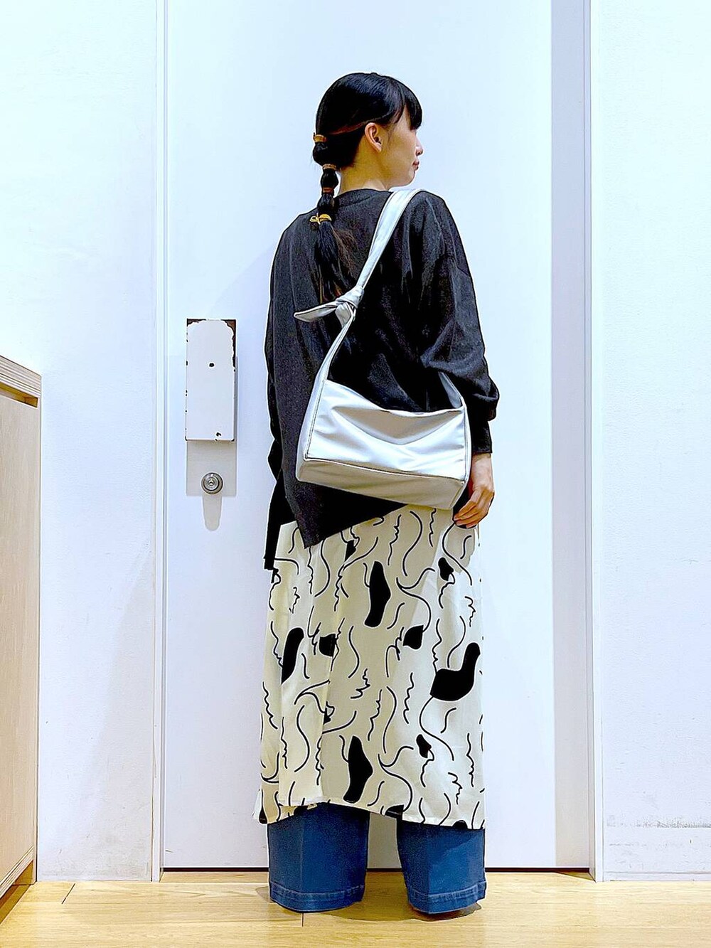 ブルー系のデニムパンツ、ベージュ系のワンピース、シルバー系のショルダーバッグを着用したレディースの春コーディネートの5枚目の写真