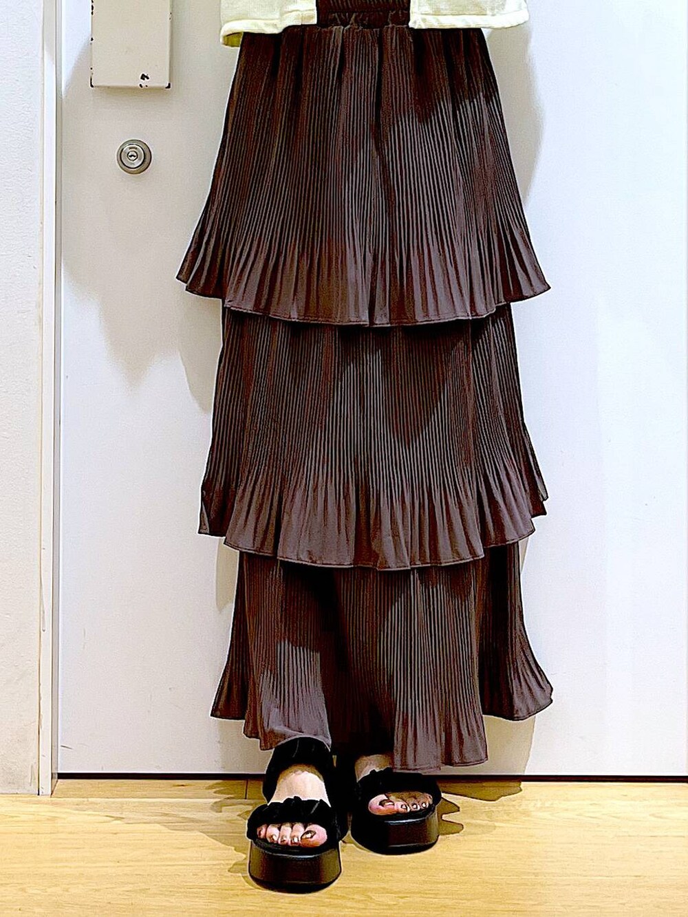 ブラウン系のスカート、ブラウン系のショルダーバッグ、ブラック系のサンダルを着用したレディースの秋コーディネートの8枚目の写真