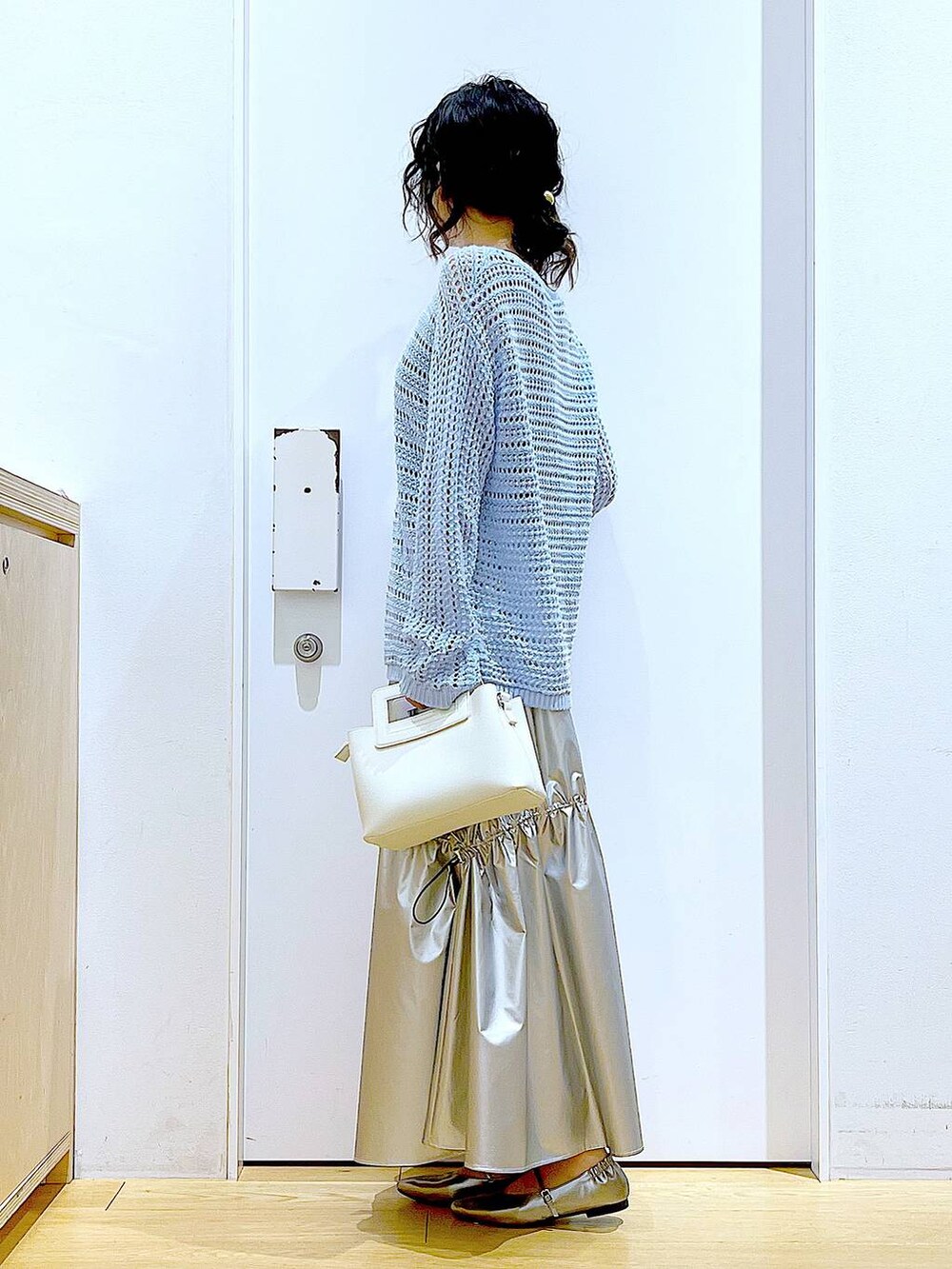 ブルー系のニット/セーター、シルバー系のスカート、ホワイト系のショルダーバッグを着用したレディースの春コーディネートの3枚目の写真
