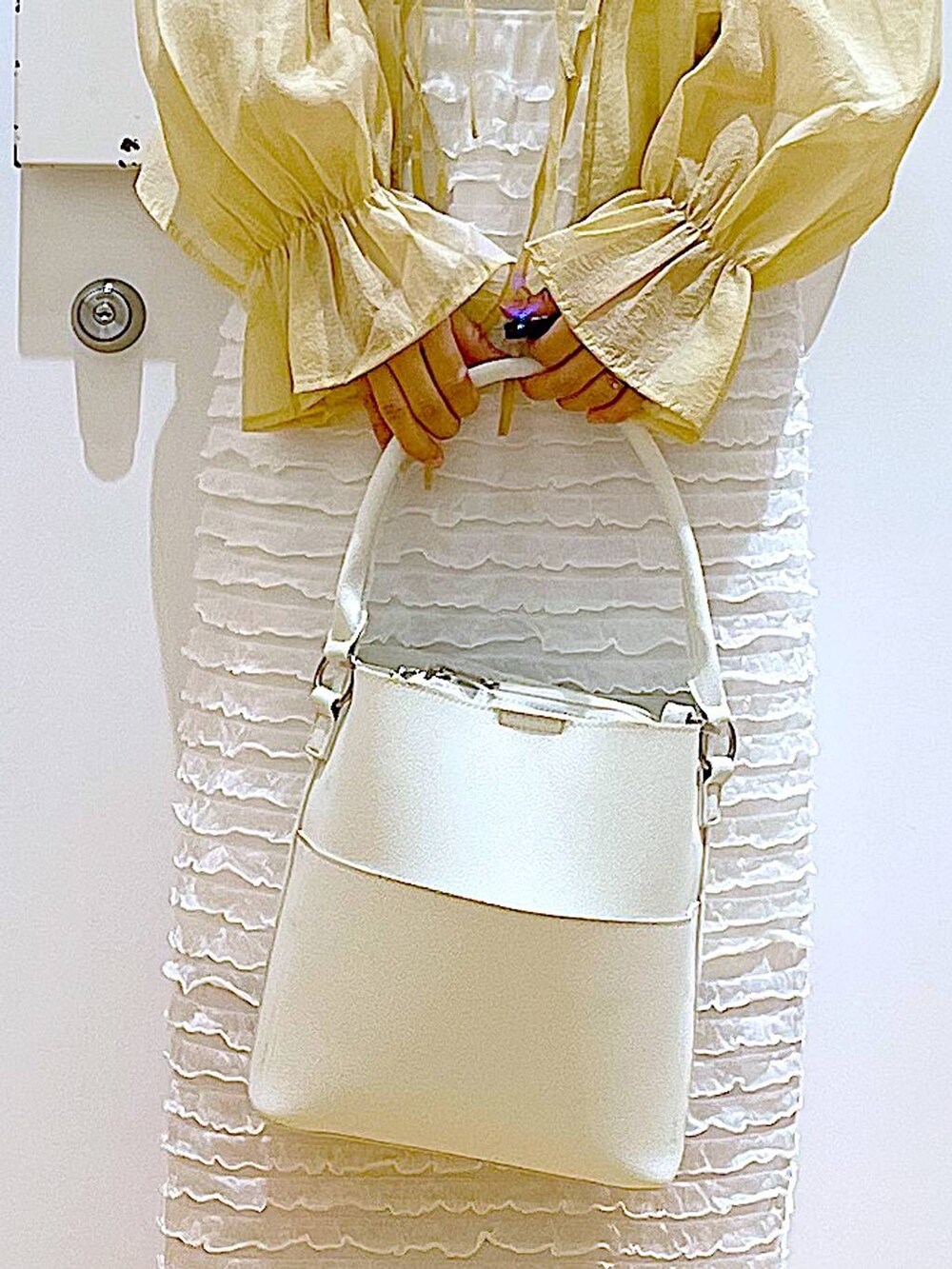 ホワイト系のベスト、ホワイト系のショルダーバッグ、ホワイト系のスカートを着用したレディースの秋コーディネートの9枚目の写真