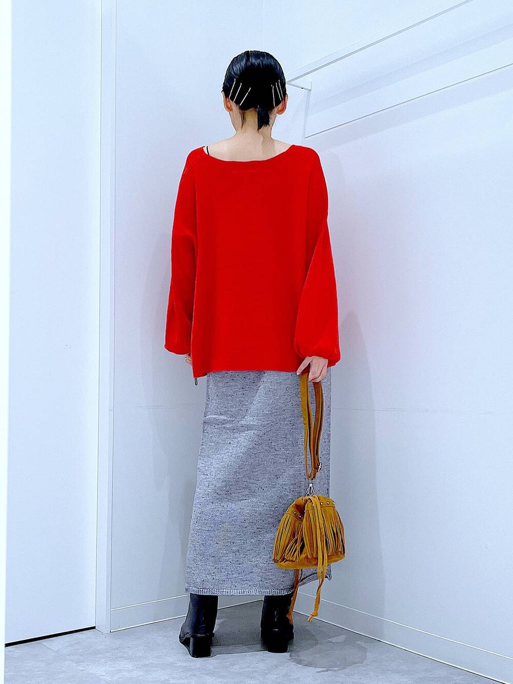 レッド系のニット/セーター、グレー系のスカート、ブラック系のブーツを着用したレディースの秋コーディネートの5枚目の写真