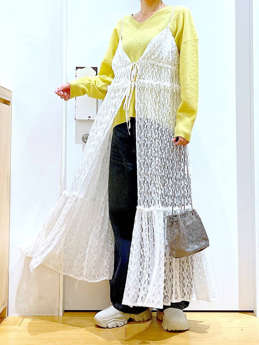 イエロー系のニット/セーター、グレー系のショルダーバッグ、ホワイト系のワンピースを着用したレディースの冬コーディネートの6枚目の写真