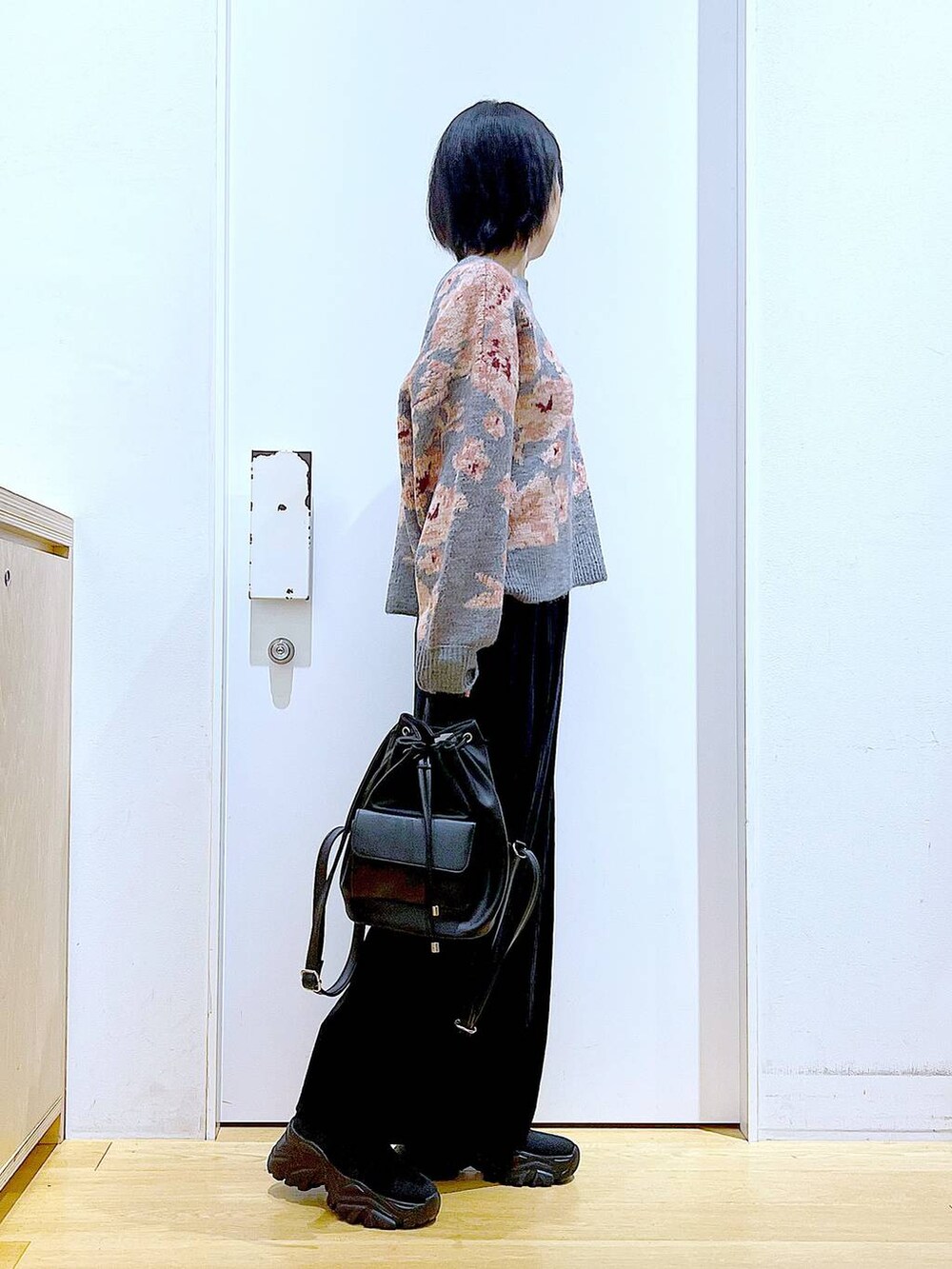 ブラック系のバックパック/リュック、ブラック系のスカート、ブラック系のブーツを着用したレディースの秋コーディネートの4枚目の写真