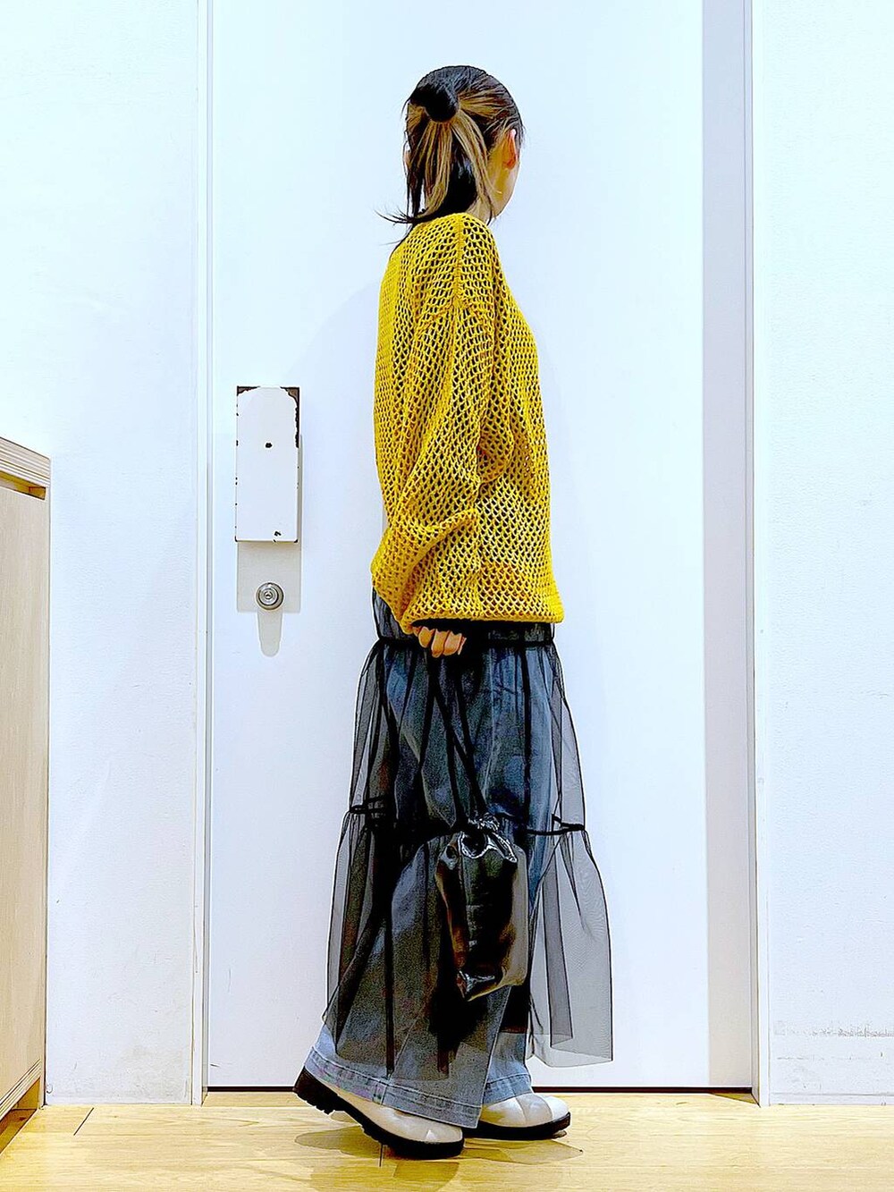 ブルー系のデニムパンツ、ブラック系のTシャツ/カットソー、オレンジ系のニット/セーターを着用したレディースの冬コーディネートの4枚目の写真