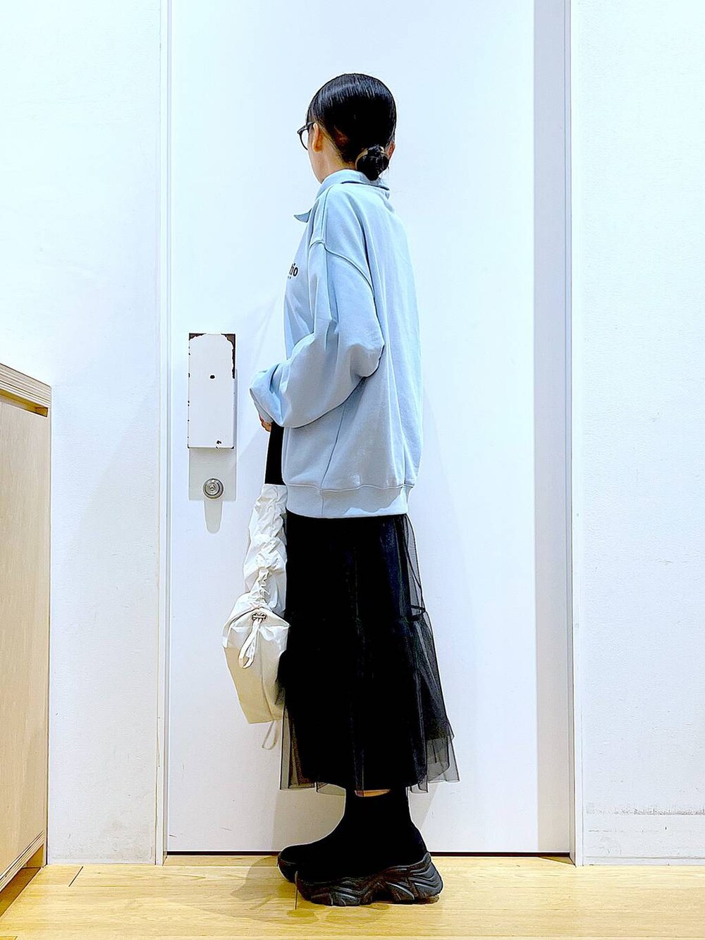 ブルー系のスウェット、ブラック系のブーツ、ホワイト系のショルダーバッグを着用したレディースの春コーディネートの3枚目の写真