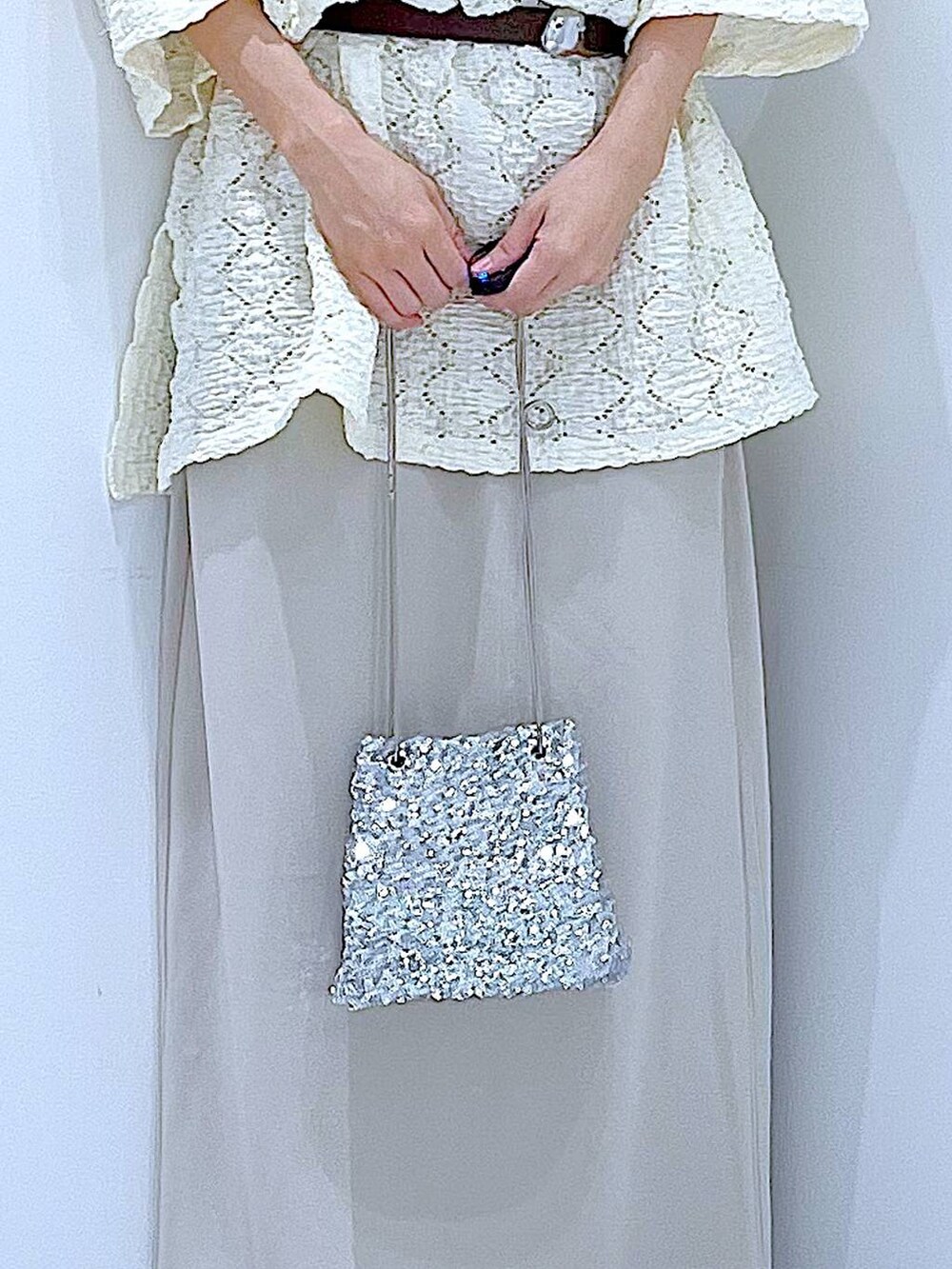 シルバー系のサンダル、ベージュ系のスカート、シルバー系のショルダーバッグを着用したレディースの夏コーディネートの9枚目の写真