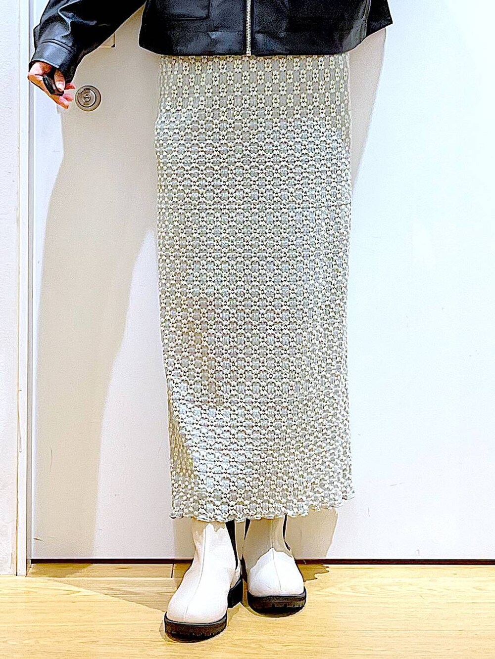 グリーン系のショルダーバッグ、ベージュ系のブーツ、グリーン系のスカートを着用したレディースの春コーディネートの8枚目の写真