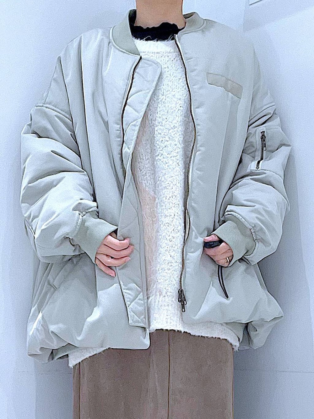 ベージュ系のニット/セーター、ブラック系のブーツ、ブラウン系のスカートを着用したレディースの冬コーディネートの7枚目の写真