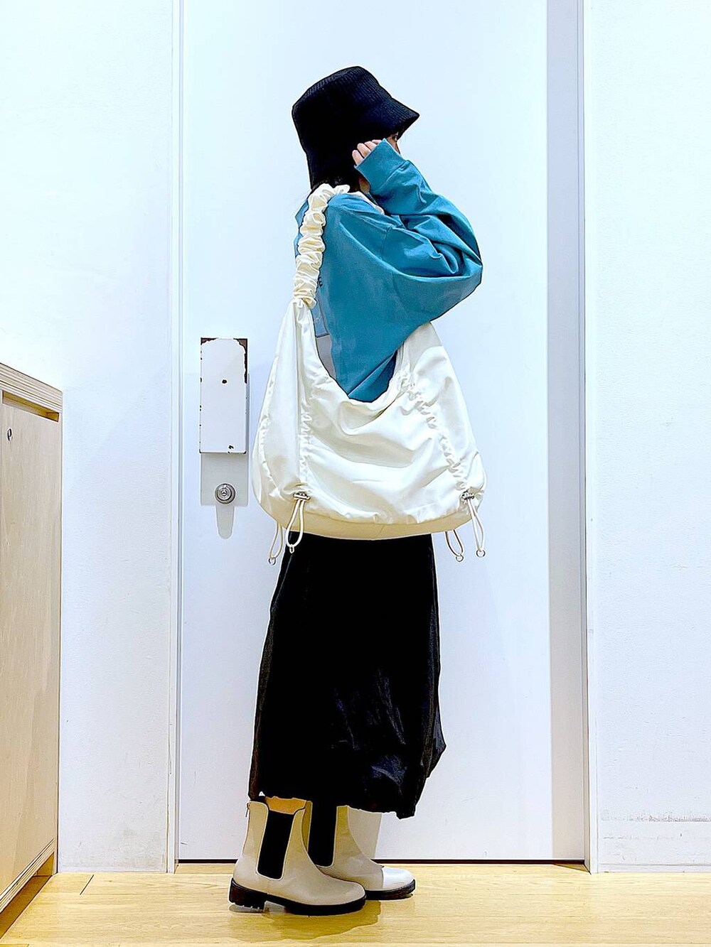 グリーン系のTシャツ/カットソー、ベージュ系のブーツ、ホワイト系のショルダーバッグを着用したレディースの春コーディネートの4枚目の写真