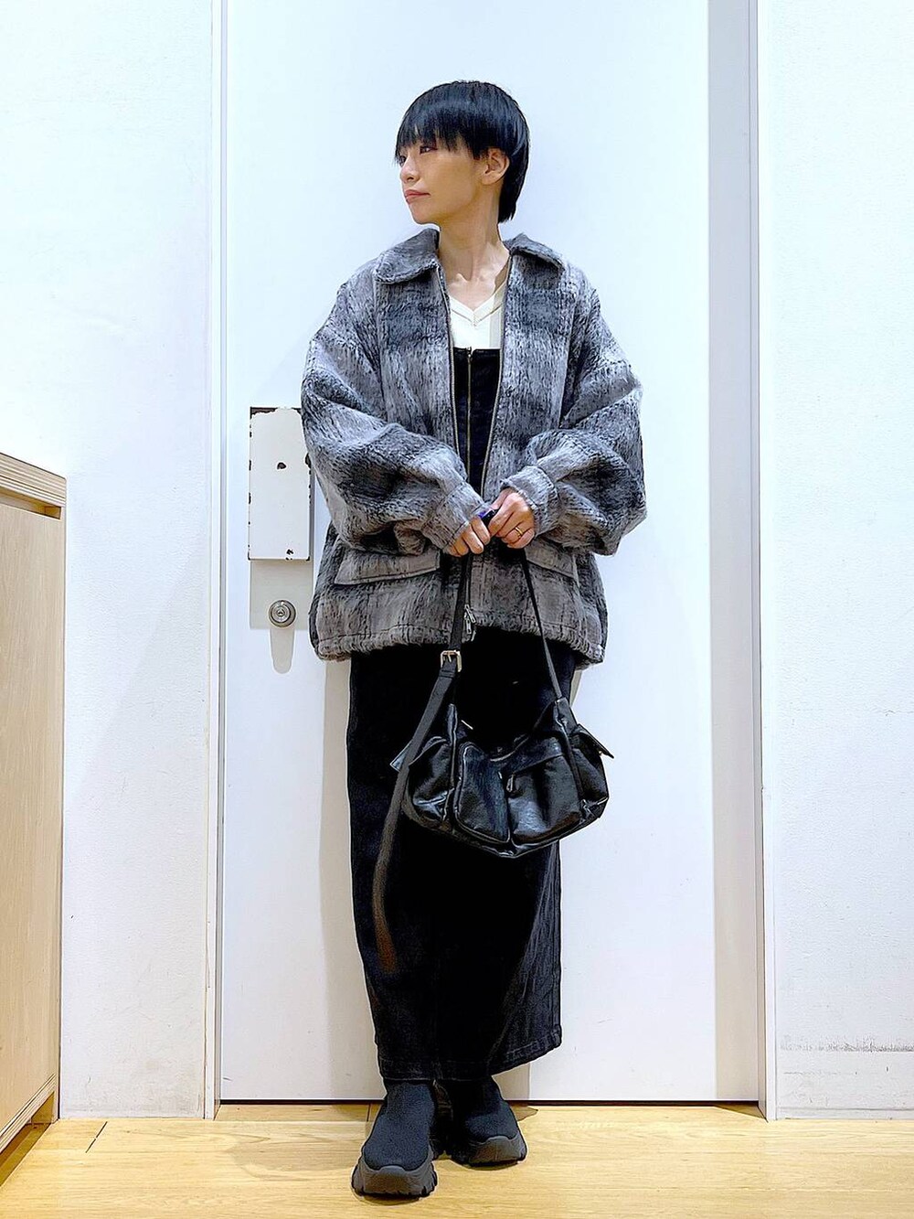 グレー系のジャンパースカート、ブラック系のブーツ、ブラック系のショルダーバッグを着用したレディースの冬コーディネートの2枚目の写真