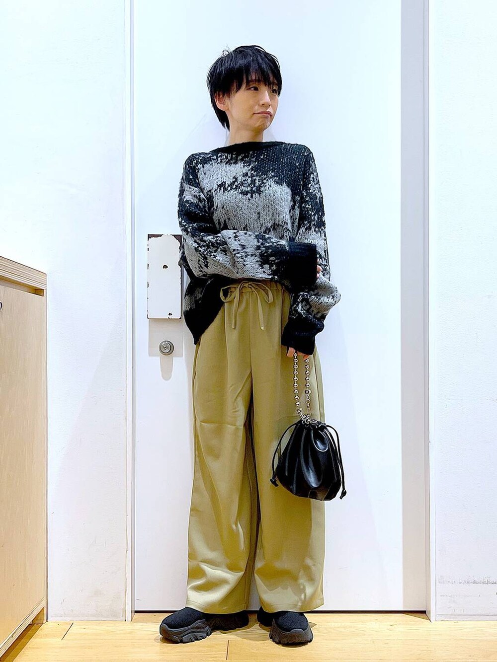 ブラック系のショルダーバッグ、ブラック系のブーツ、イエロー系のその他パンツを着用したレディースの冬コーディネートの2枚目の写真