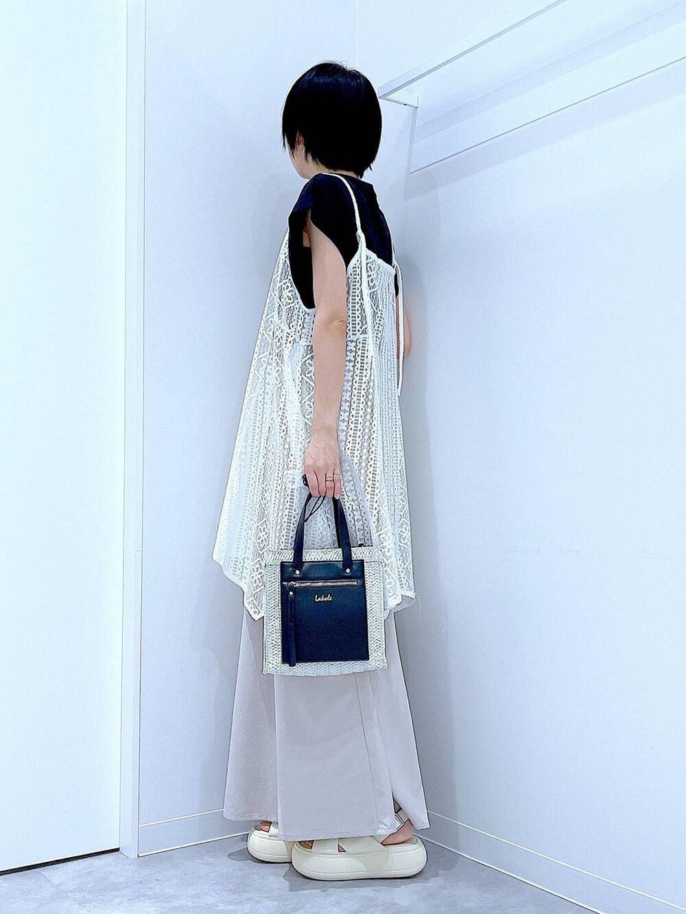 ホワイト系のショルダーバッグ、ホワイト系のサンダル、ブラック系のTシャツ/カットソーを着用したレディースの夏コーディネートの3枚目の写真