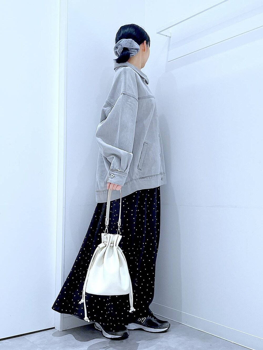 グレー系のデニムジャケット、ホワイト系のショルダーバッグ、グレー系のシュシュを着用したレディースの春コーディネートの4枚目の写真