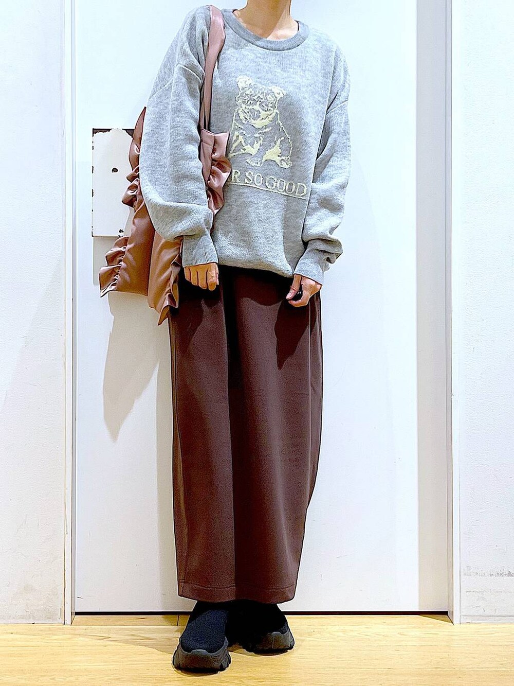 ブラック系のブーツ、ピンク系のトートバッグ、ブラウン系のスカートを着用したレディースの冬コーディネートの6枚目の写真