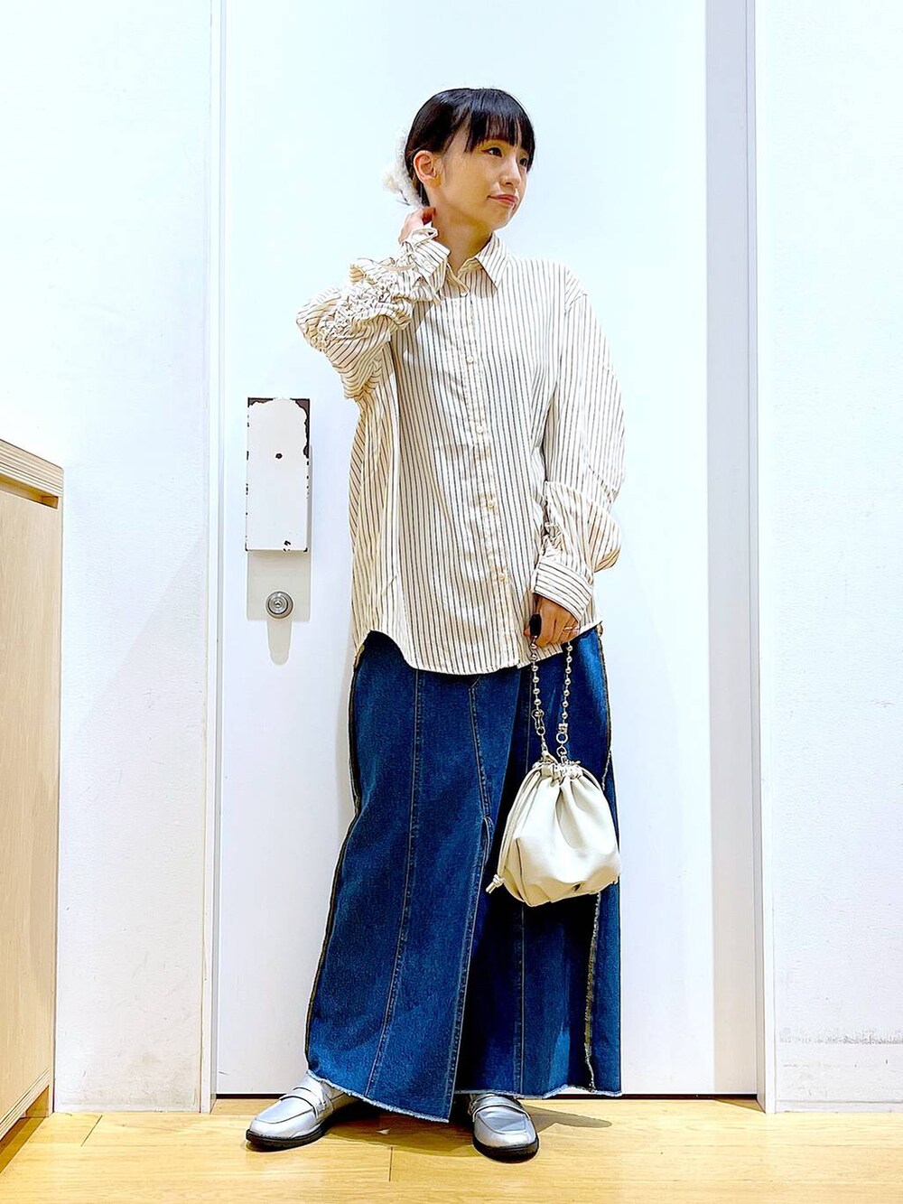 ベージュ系のショルダーバッグ、シルバー系のローファー、ブルー系のデニムスカートを着用したレディースの秋コーディネートの2枚目の写真