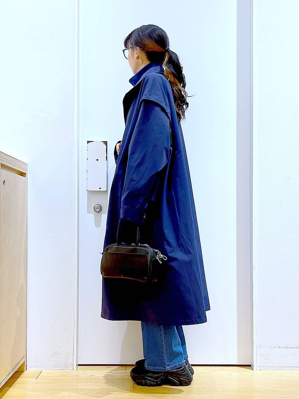 ブラック系のショルダーバッグ、ブルー系のデニムパンツ、ブルー系のその他アウターを着用したレディースの冬コーディネートの3枚目の写真