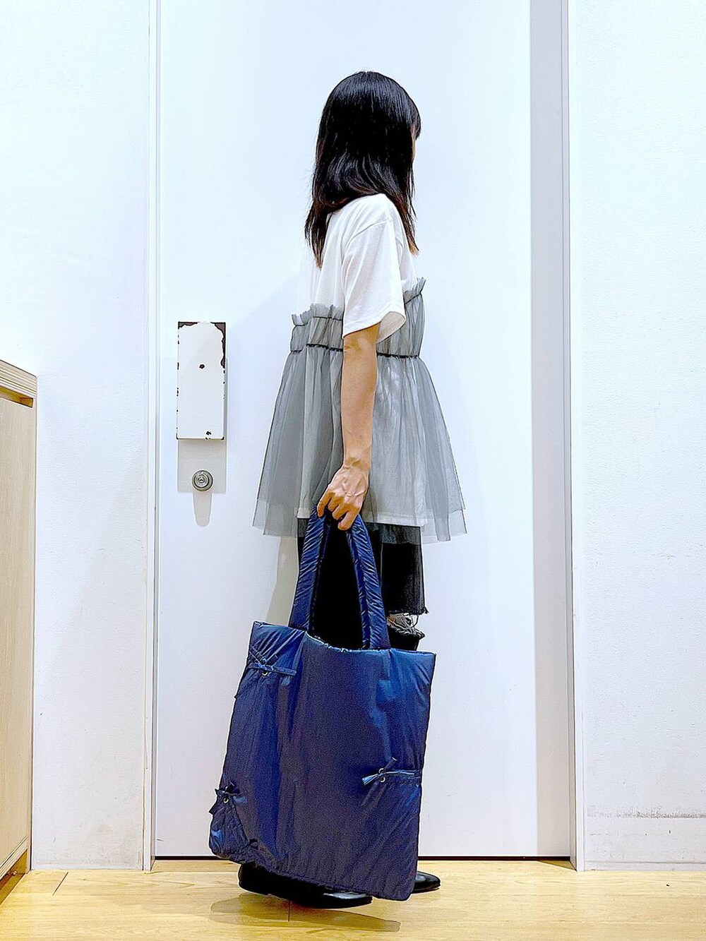 グレー系のTシャツ/カットソー、ブラック系のデニムパンツ、ブルー系のトートバッグを着用したレディースの秋コーディネートの4枚目の写真