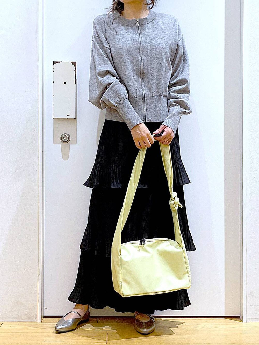 ブラック系のカーディガン/ボレロ、ブラック系のスカート、イエロー系のショルダーバッグを着用したレディースの春コーディネートの6枚目の写真