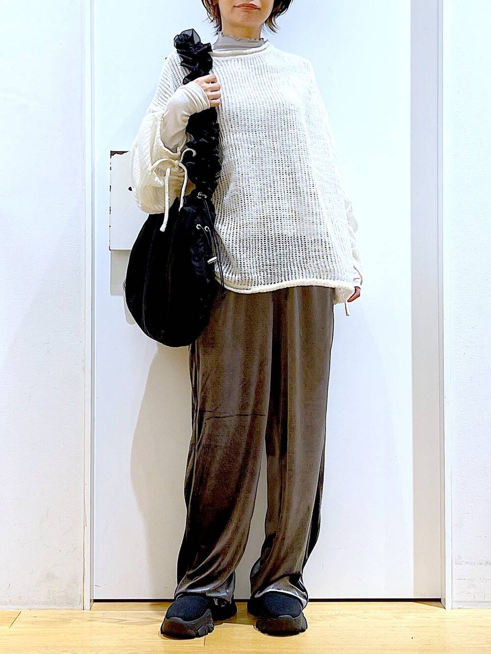 ブラック系のショルダーバッグ、ブラック系のブーツ、ホワイト系のニット/セーターを着用したレディースの冬コーディネートの6枚目の写真