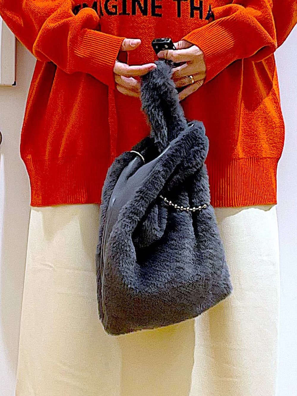 グレー系のショルダーバッグ、オレンジ系のニット/セーター、ブラック系のブーツを着用したレディースの冬コーディネートの9枚目の写真