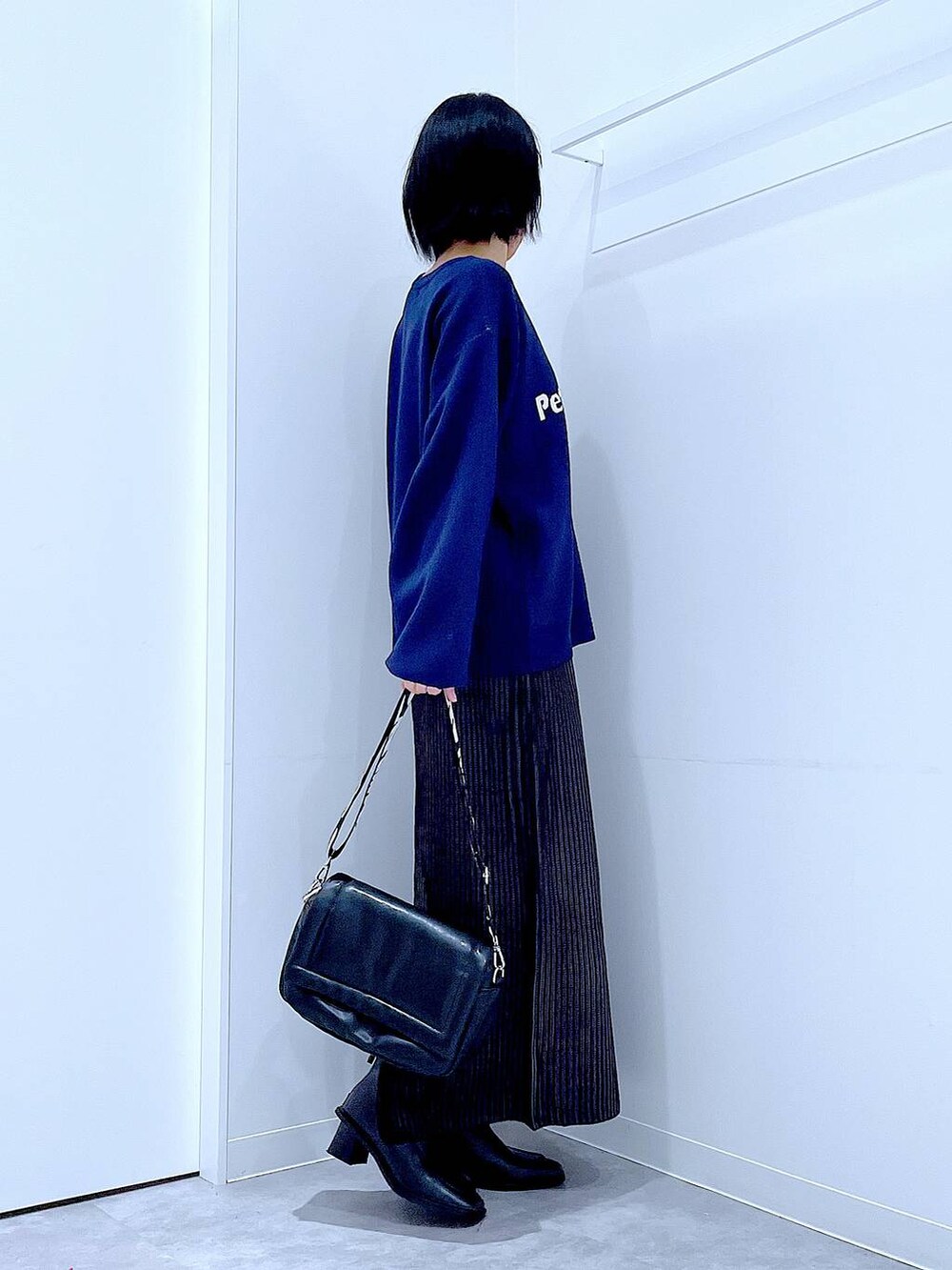 ブラック系のスカート、ブラック系のショルダーバッグ、ブラック系のブーツを着用したレディースの冬コーディネートの4枚目の写真