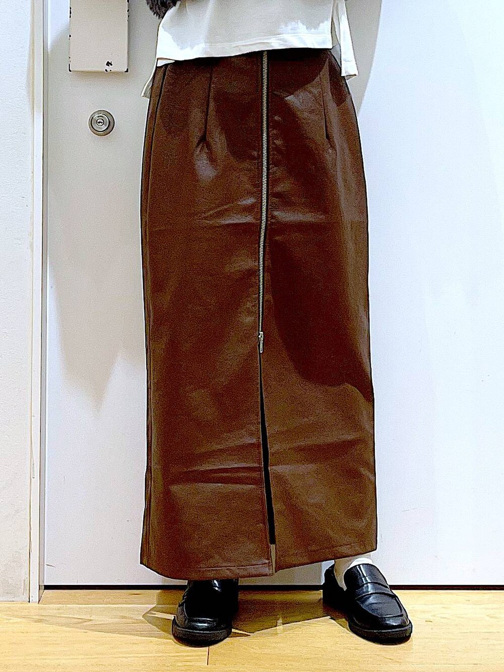 ブラウン系のスカート、グレー系のベスト、ブラック系のローファーを着用したレディースの秋コーディネートの8枚目の写真