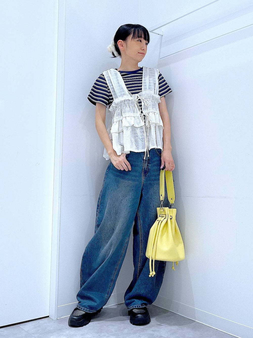 ブルー系のデニムパンツ、イエロー系のショルダーバッグ、ブラック系のスニーカーを着用したレディースの春コーディネートの2枚目の写真