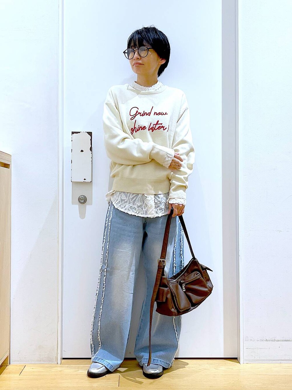 シルバー系のローファー、ブラウン系のショルダーバッグ、ホワイト系のニット/セーターを着用したレディースの春コーディネートの2枚目の写真