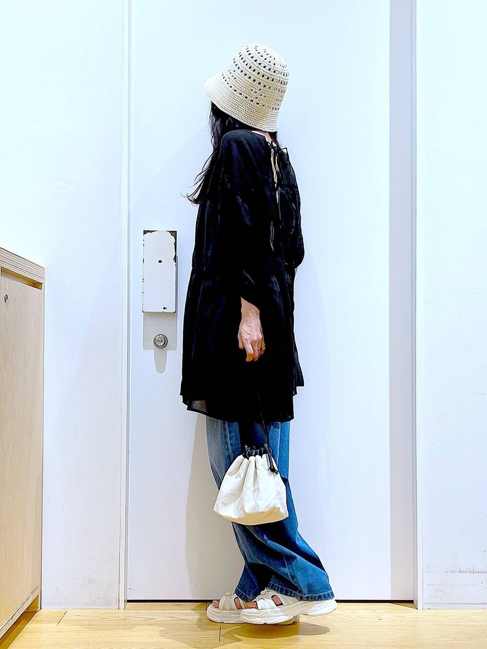 ホワイト系のショルダーバッグ、ブルー系のデニムパンツ、ホワイト系のサンダルを着用したレディースの夏コーディネートの3枚目の写真