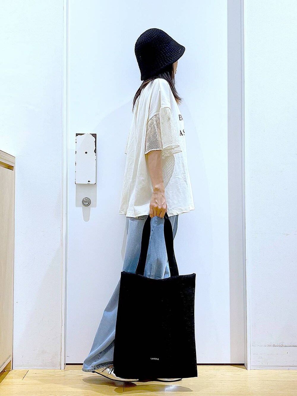 ブラック系のトートバッグ、ブルー系のデニムパンツ、シルバー系のパンプスを着用したレディースの夏コーディネートの4枚目の写真