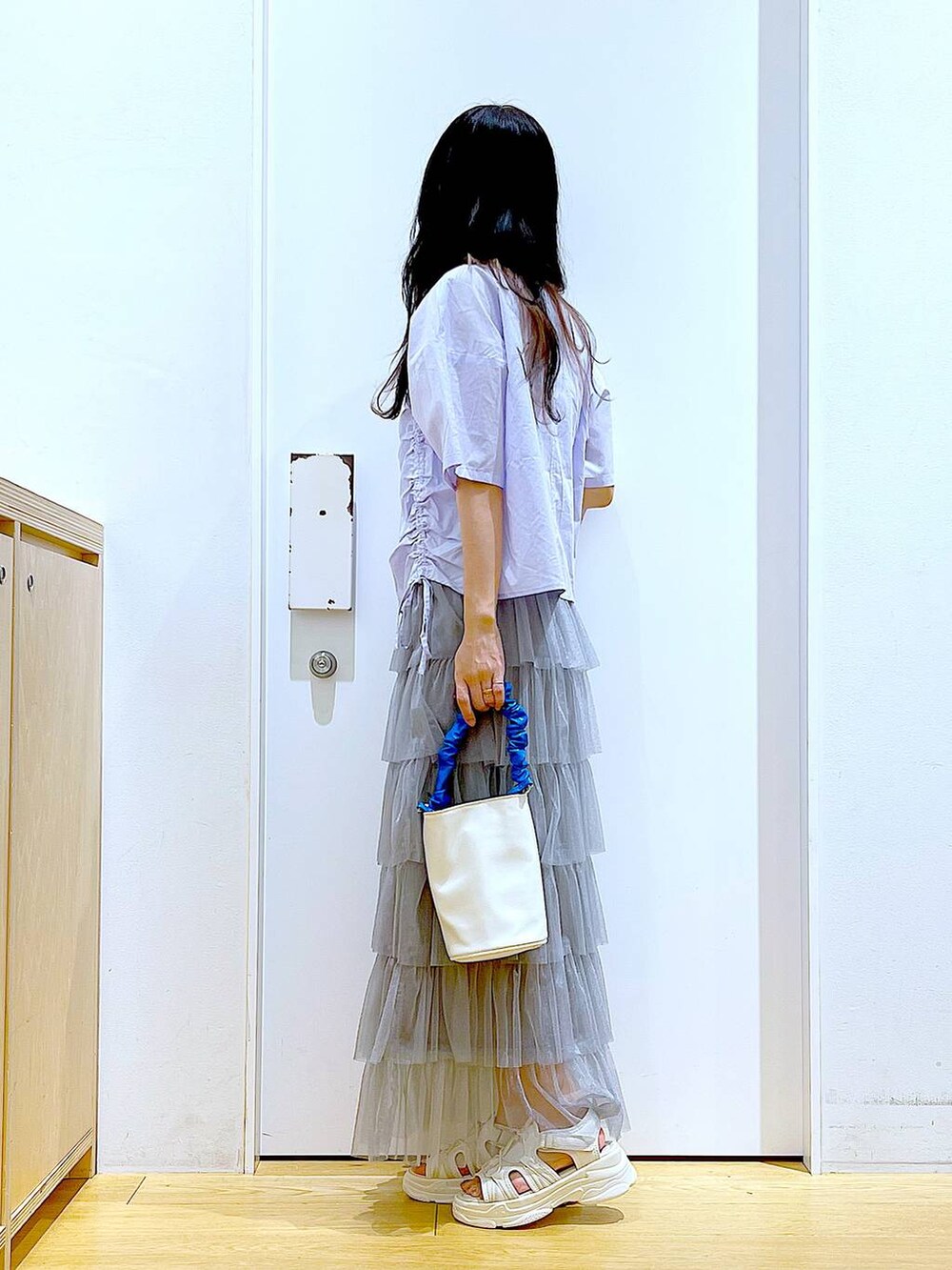 ブルー系のショルダーバッグ、ホワイト系のサンダル、グレー系のスカートを着用したレディースの夏コーディネートの3枚目の写真
