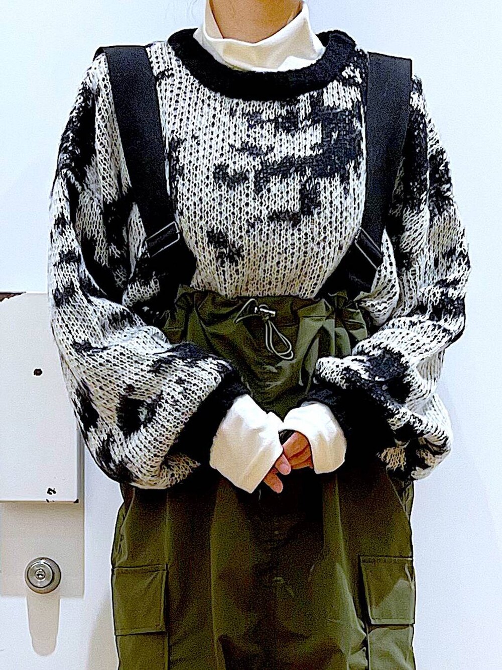 ホワイト系のトートバッグ、ベージュ系のTシャツ/カットソー、グリーン系のジャンパースカートを着用したレディースの冬コーディネートの7枚目の写真