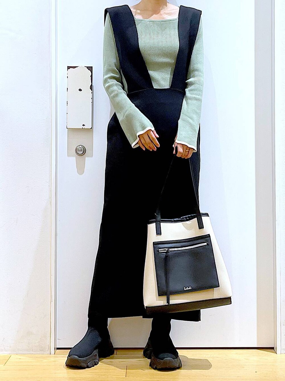 グリーン系のニット/セーター、ブラック系のブーツ、ブラック系のサロペット/オーバーオールを着用したレディースの冬コーディネートの6枚目の写真