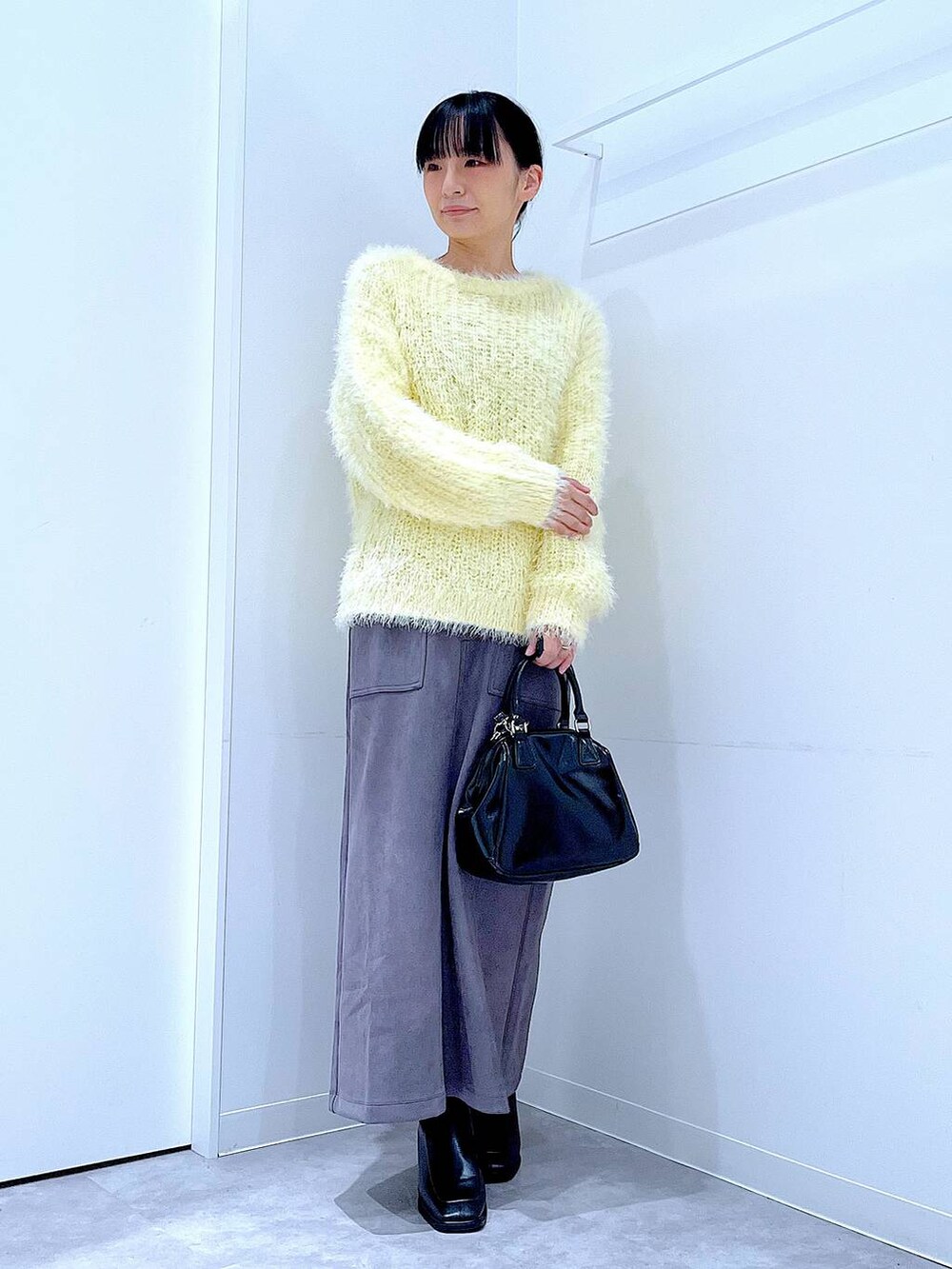 ブラック系のブーツ、イエロー系のニット/セーター、ブラック系のショルダーバッグを着用したレディースの冬コーディネートの2枚目の写真