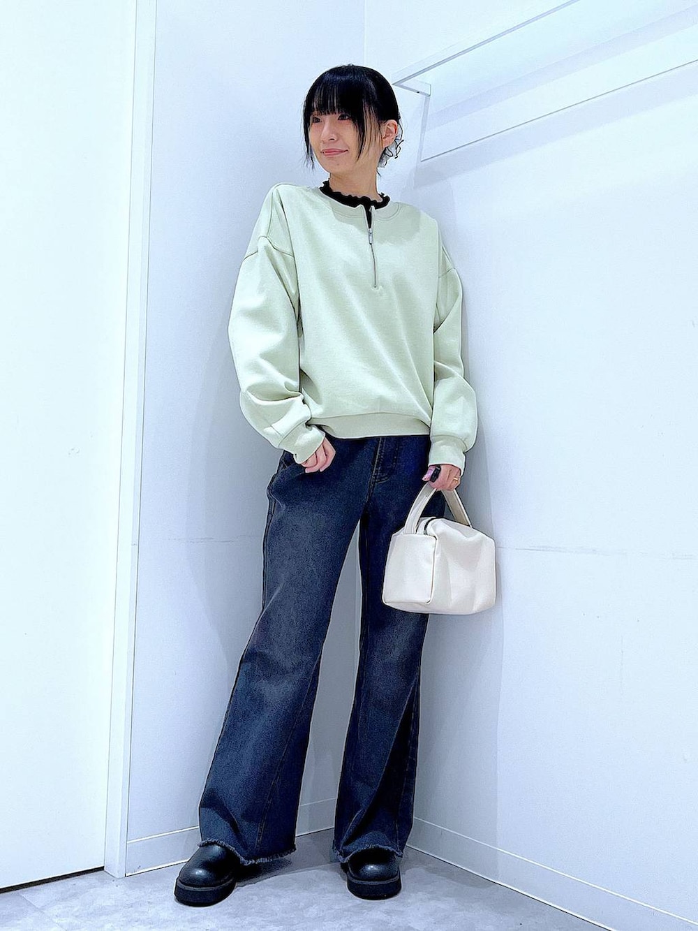 ホワイト系のショルダーバッグ、グリーン系のスウェット、ブラック系のデニムパンツを着用したレディースの春コーディネートの2枚目の写真