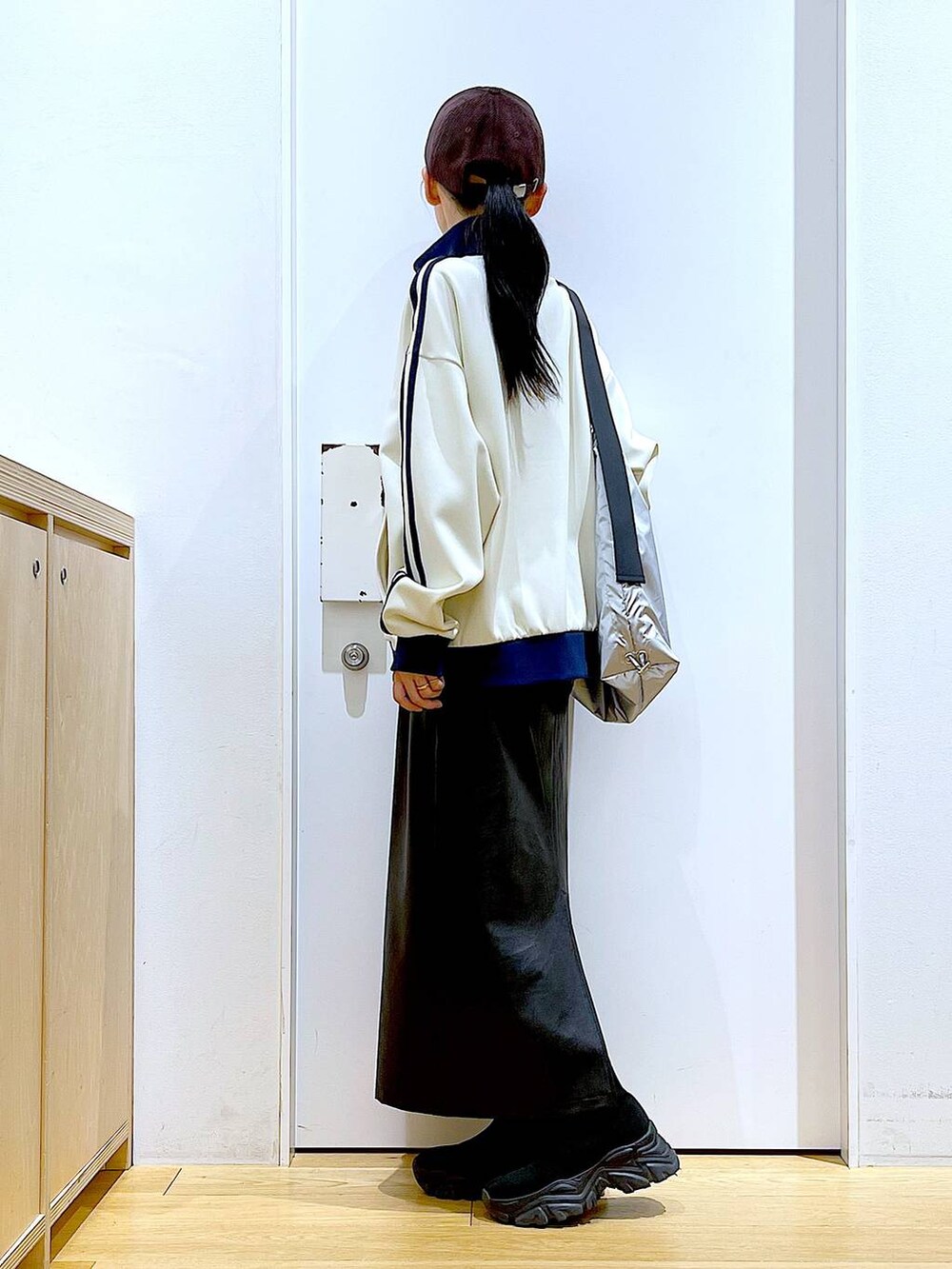 ブラック系のブーツ、ブラック系のスカート、シルバー系のショルダーバッグを着用したレディースの冬コーディネートの3枚目の写真