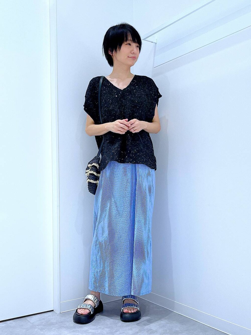 ブラック系のショルダーバッグ、シルバー系のサンダル、ブラック系のベストを着用したレディースの夏コーディネートの2枚目の写真