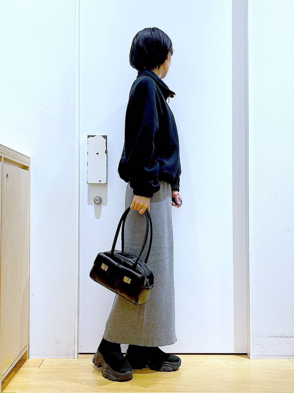 ブラック系のハンドバッグ、ブラック系のブーツ、グレー系のスカートを着用したレディースの冬コーディネートの4枚目の写真