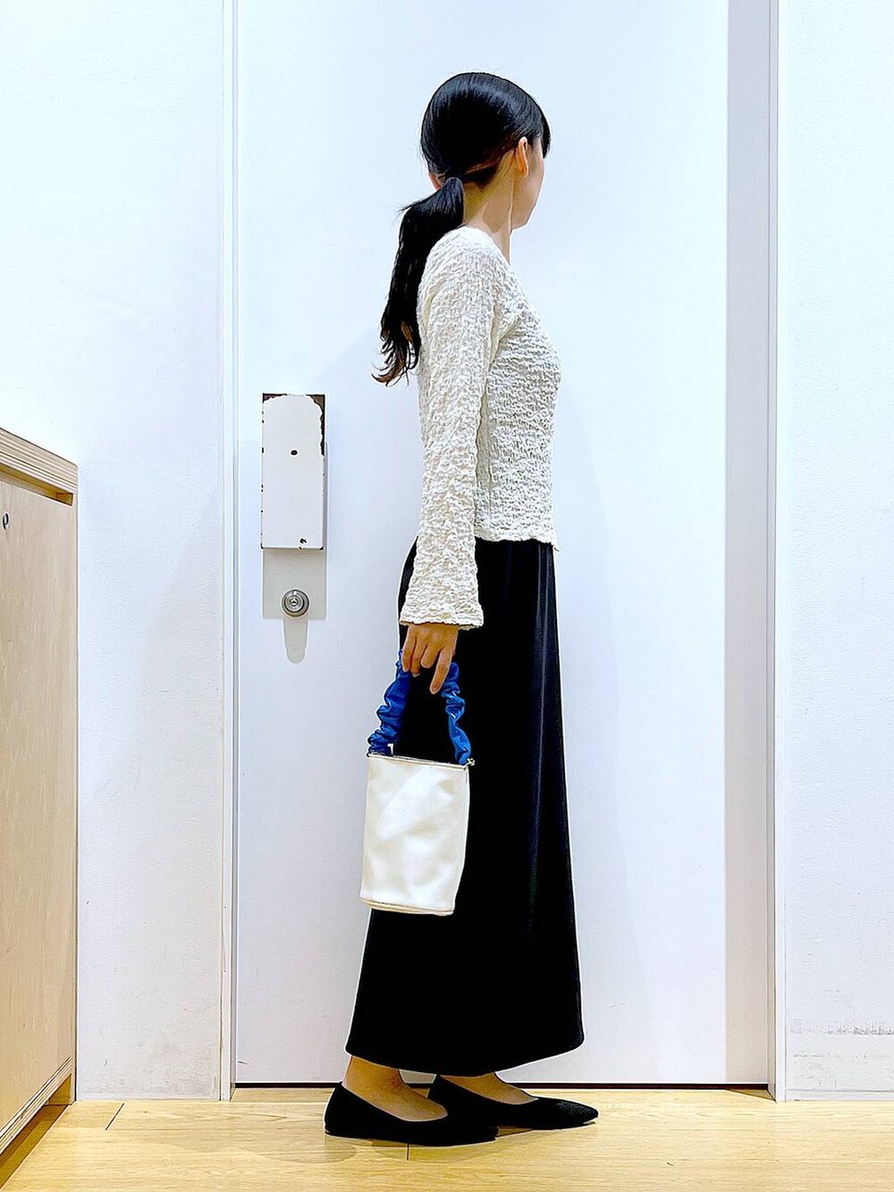 ブルー系のショルダーバッグ、ブラック系のパンプス、ブラック系のワンピースを着用したレディースの春コーディネートの4枚目の写真