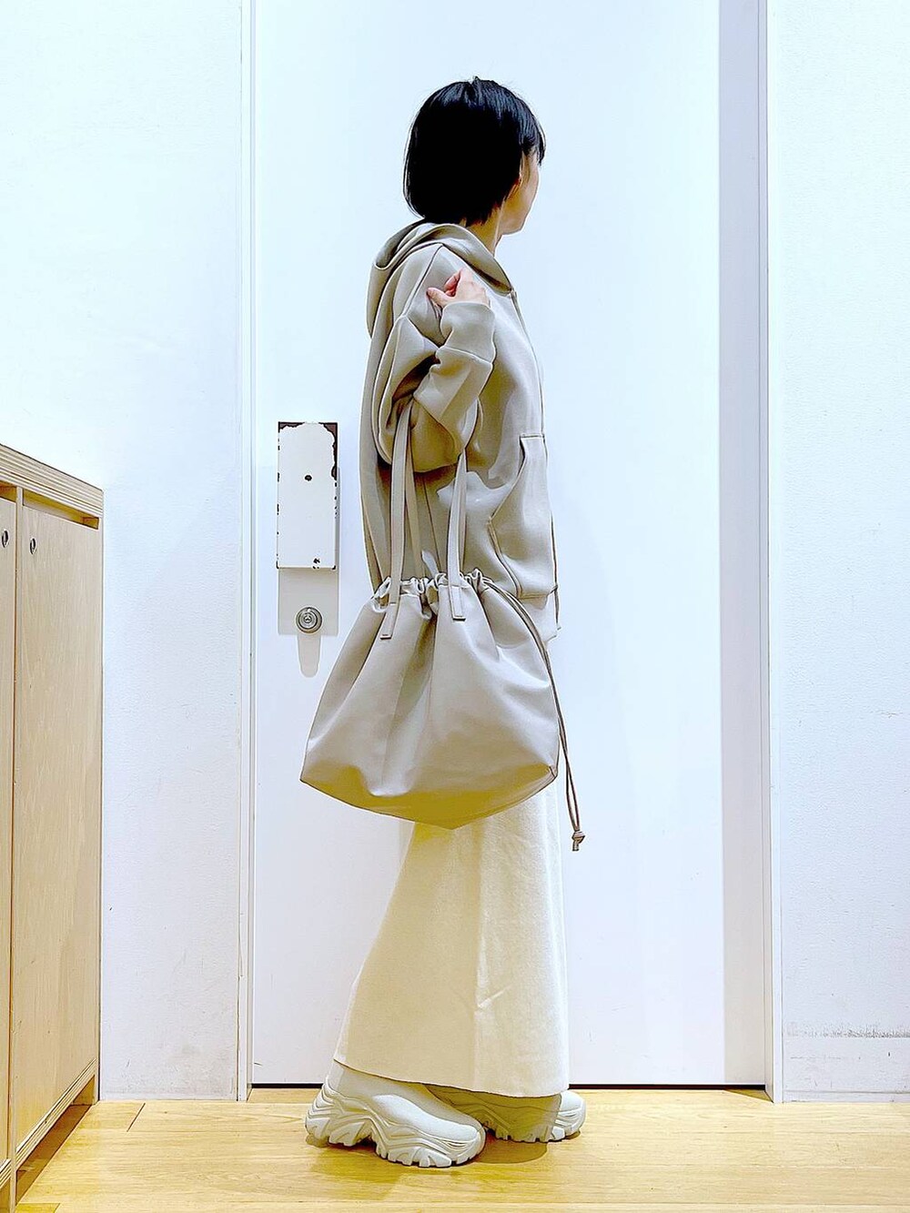 ベージュ系のトートバッグ、ベージュ系のブーツ、ベージュ系のスカートを着用したレディースの秋コーディネートの4枚目の写真