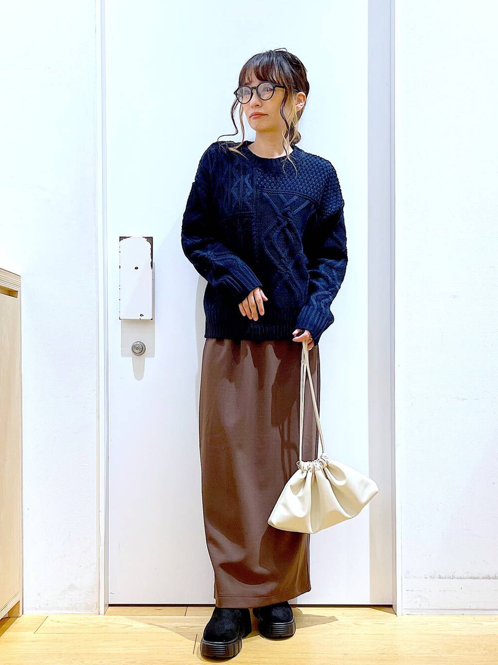 ブラック系のブーツ、ベージュ系のショルダーバッグ、ブラウン系のスカートを着用したレディースの冬コーディネートの2枚目の写真