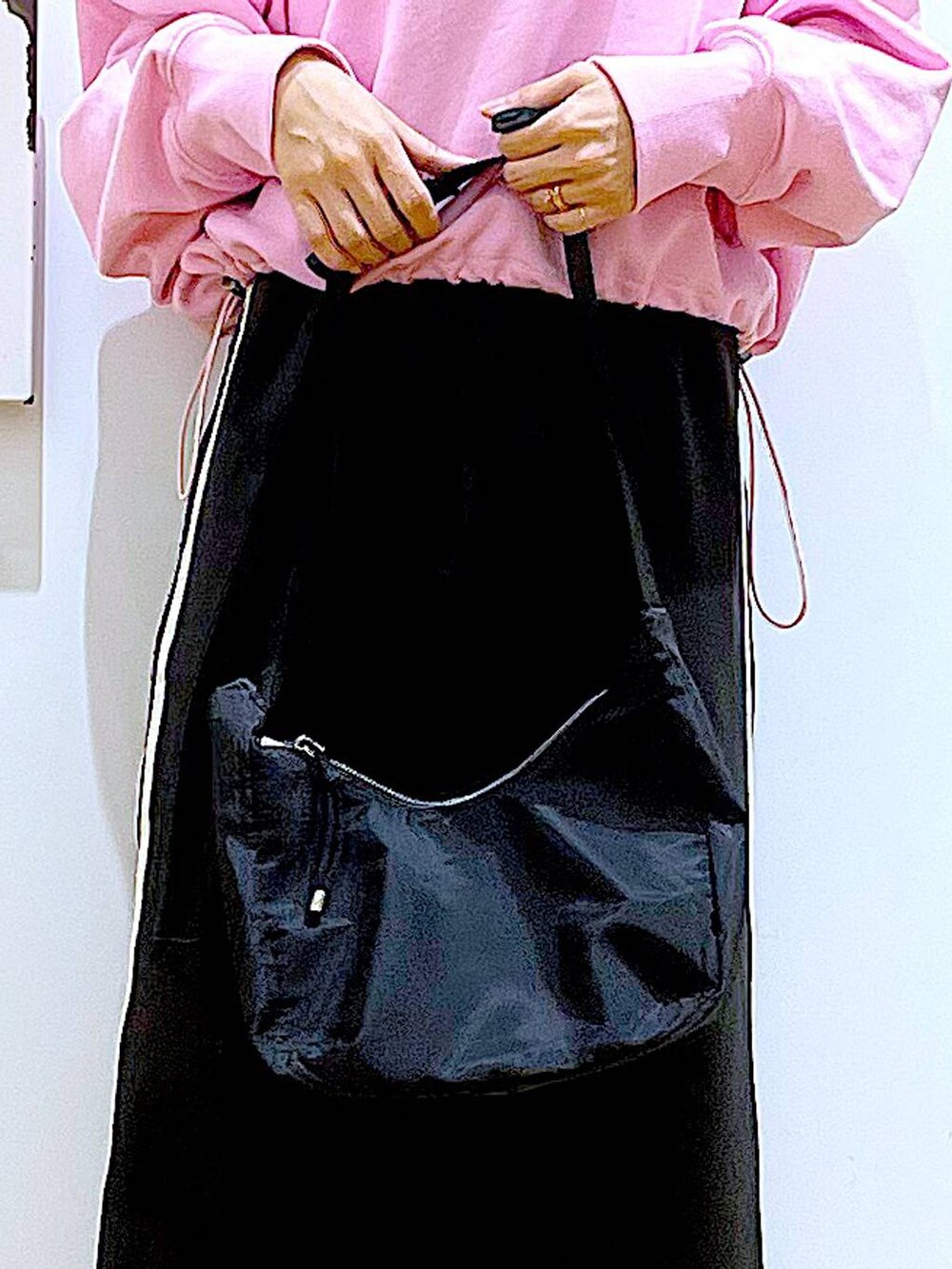 ピンク系のスウェット、ベージュ系のブーツ、ブラック系のショルダーバッグを着用したレディースの春コーディネートの9枚目の写真